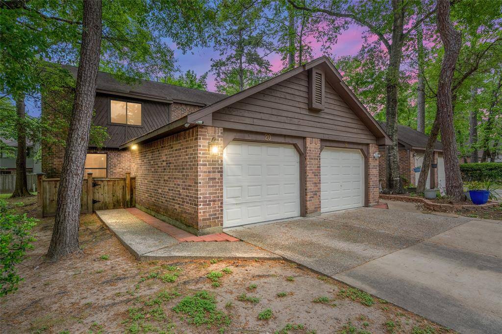 Welcome home to 20 W Willowwood Ct, your charming two-story brick home nestled among mature trees. The exterior features a single garage and concrete walkway, offering a welcoming and serene environment.