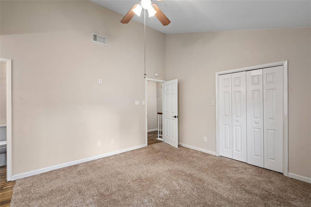 Your primary bedroom has a ceiling fan with traditional lighting, neutral beige walls, carpeted flooring and a closet with double doors.