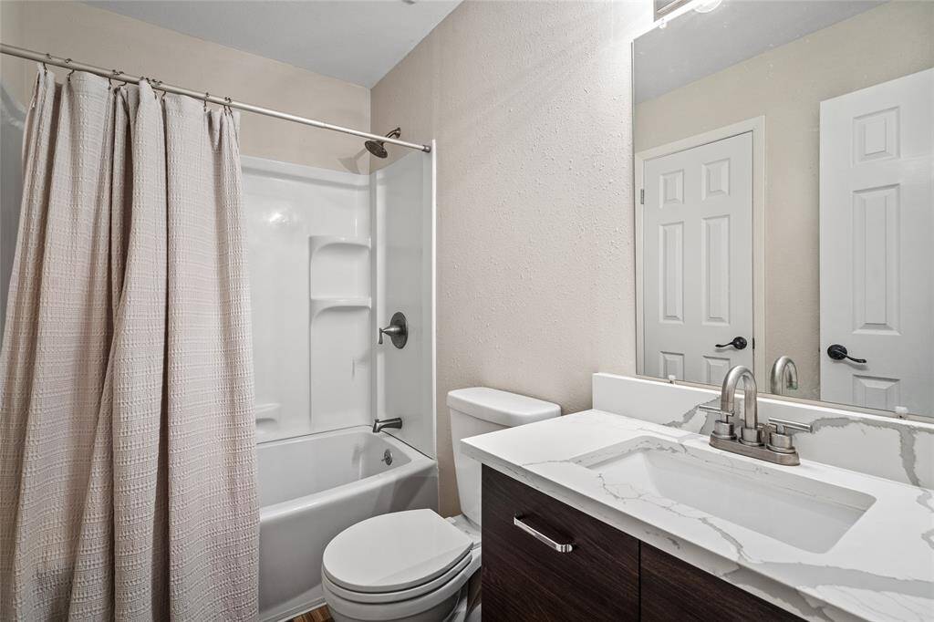 Your main bathroom features a modern design with a sleek vanity, quartz countertop, and a large mirror. It includes a tub/shower combo, neutral walls, and contemporary fixtures, offering a clean and inviting space.