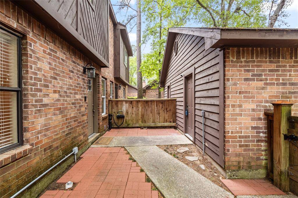 A view of the back of the garage and private front patio area. It is framed by a wooden fence offering a cozy outdoor space ideal for relaxation.