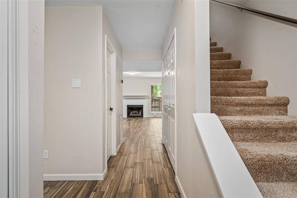 Your welcoming entryway leads to a cozy living area featuring a fireplace. There is a carpeted staircase to the upper level on the right. The space is bright and inviting.