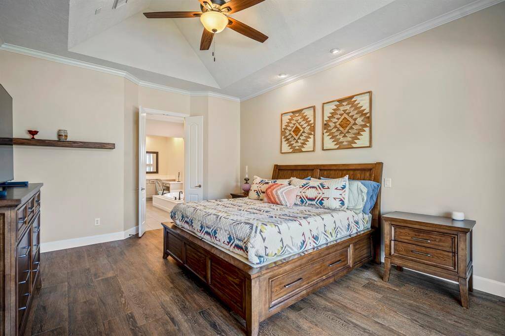 Step into the serene primary suite, where vaulted ceilings, recessed lighting, and a ceiling fan create a tranquil retreat. Plush wood-look flooring adds warmth.