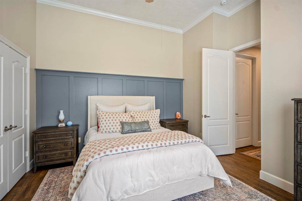 This stylish downstairs bedroom features a bold board and batten accent wall, high ceilings, wood-look flooring, and easy access to a full bath—perfect for guests!