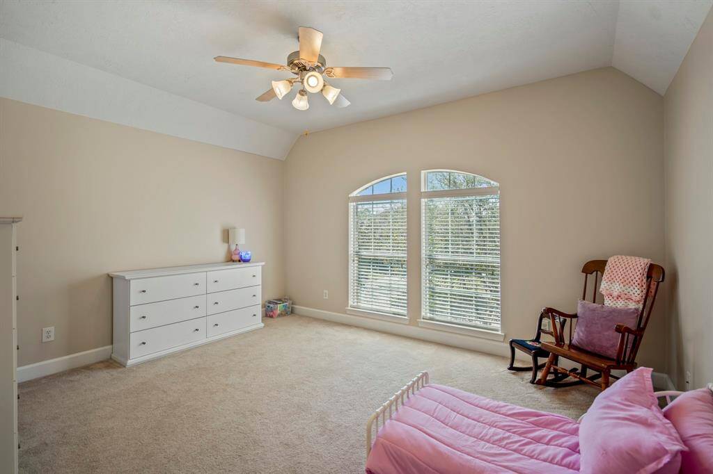 This spacious upstairs bedroom boasts vaulted ceilings and oversized windows, filling the room with natural light.