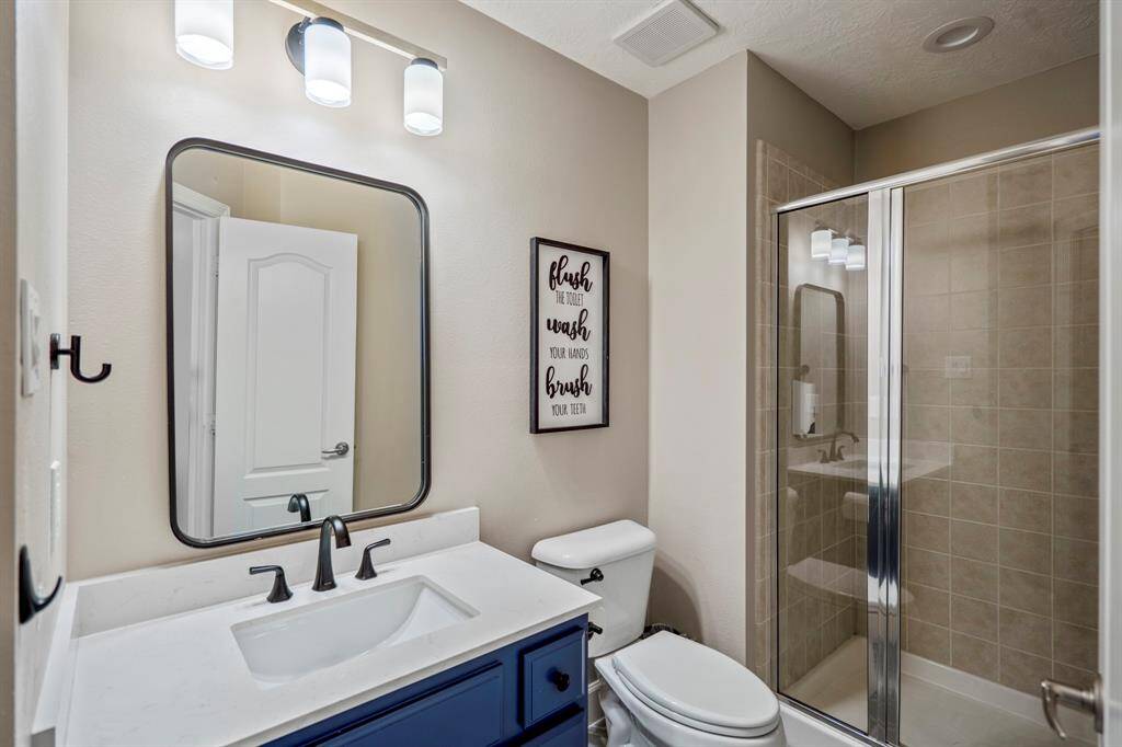 The ensuite bath boasts a sleek quartz vanity, modern black fixtures, and a tiled walk-in shower, combining style and functionality for a private retreat.