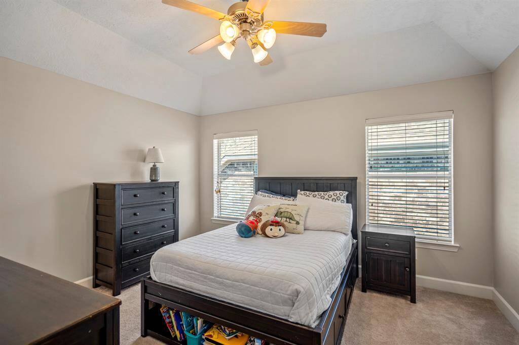 The 3rd upstairs bedroom features vaulted ceilings, abundant natural light, and neutral tones, creating a bright and inviting atmosphere.