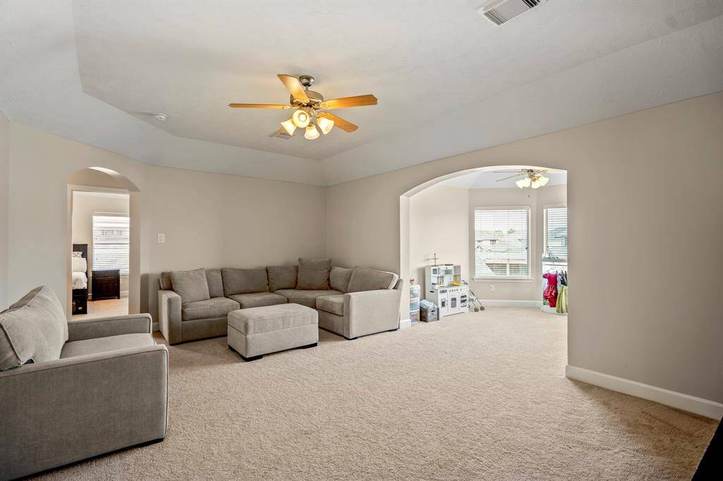 The game room’s oversized windows flood the space with natural light, offering serene neighborhood views and a welcoming ambiance.