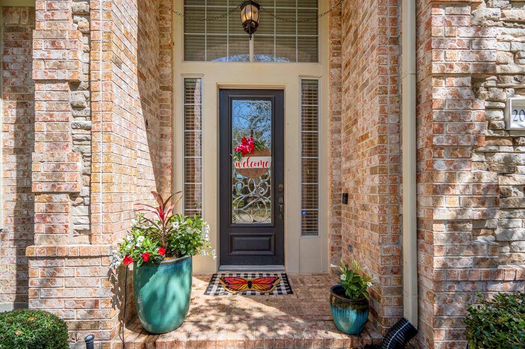 Step onto the charming front porch, where a custom glass-paneled door welcomes you into a warm and inviting entryway, setting the tone for the timeless elegance found throughout the home.