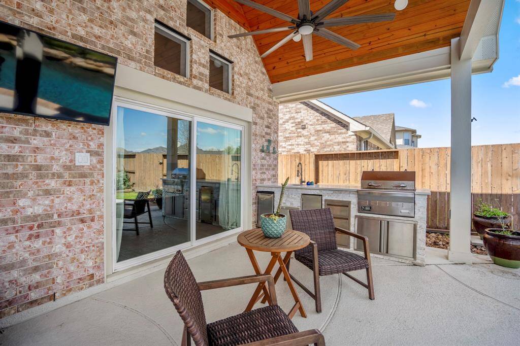 Outdoor living at its finest—covered patio with vaulted ceilings, built-in outdoor kitchen, and ceiling fans, creating the ideal setting for year-round enjoyment.