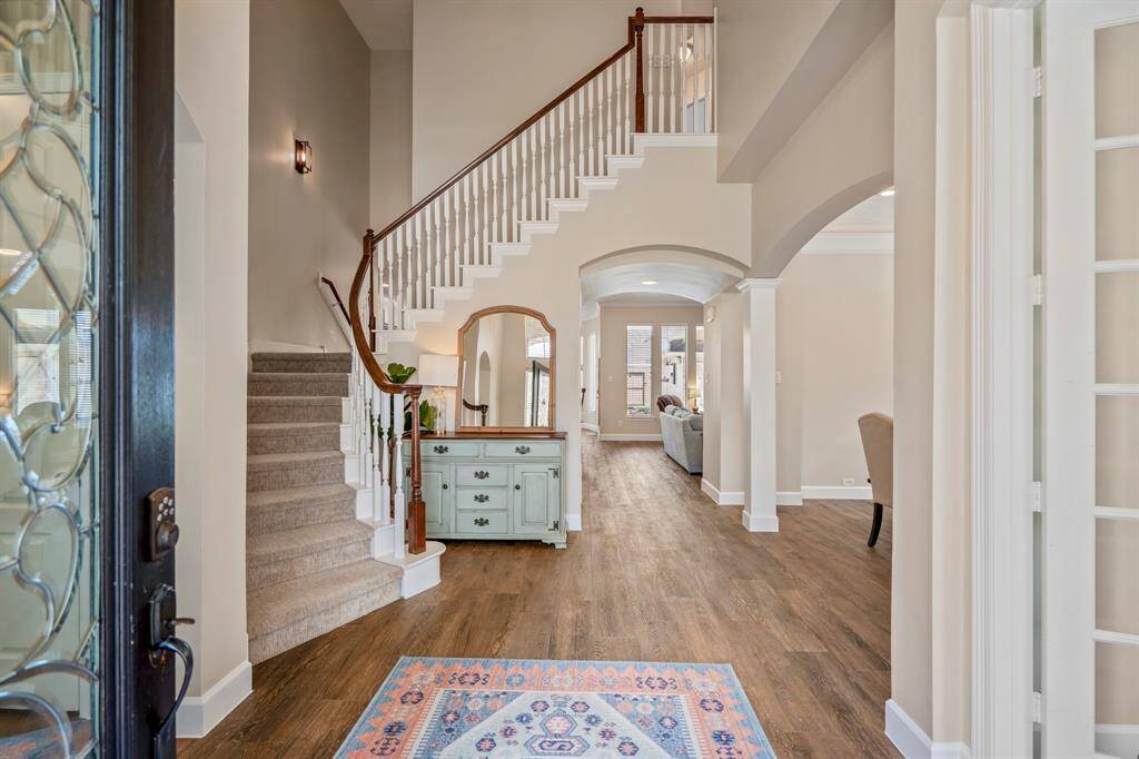 Inside, the grand foyer impresses with soaring ceilings, a dramatic curved staircase, and an open-concept design that seamlessly connects the main living areas.
