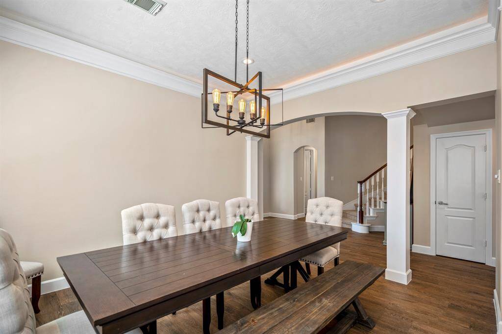 The formal dining room is a sophisticated space for entertaining, featuring elegant crown molding, tray ceilings, and a statement chandelier that adds a touch of modern charm.