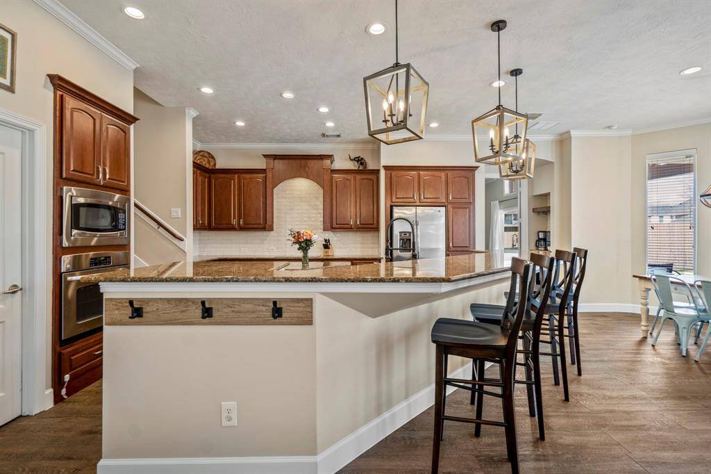 The gourmet kitchen is a chef’s dream, featuring rich wood cabinetry, granite countertops, and a large island with bar seating for casual dining.