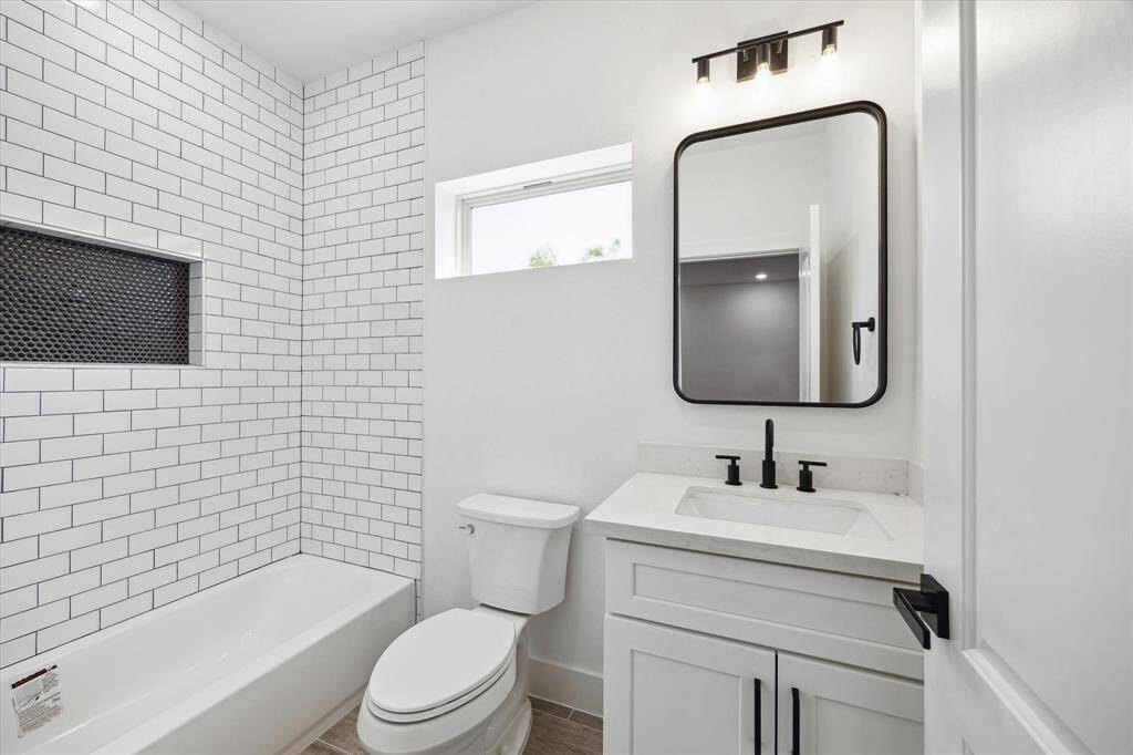 Secondary bathroom with subway tiled wall and black hardware.