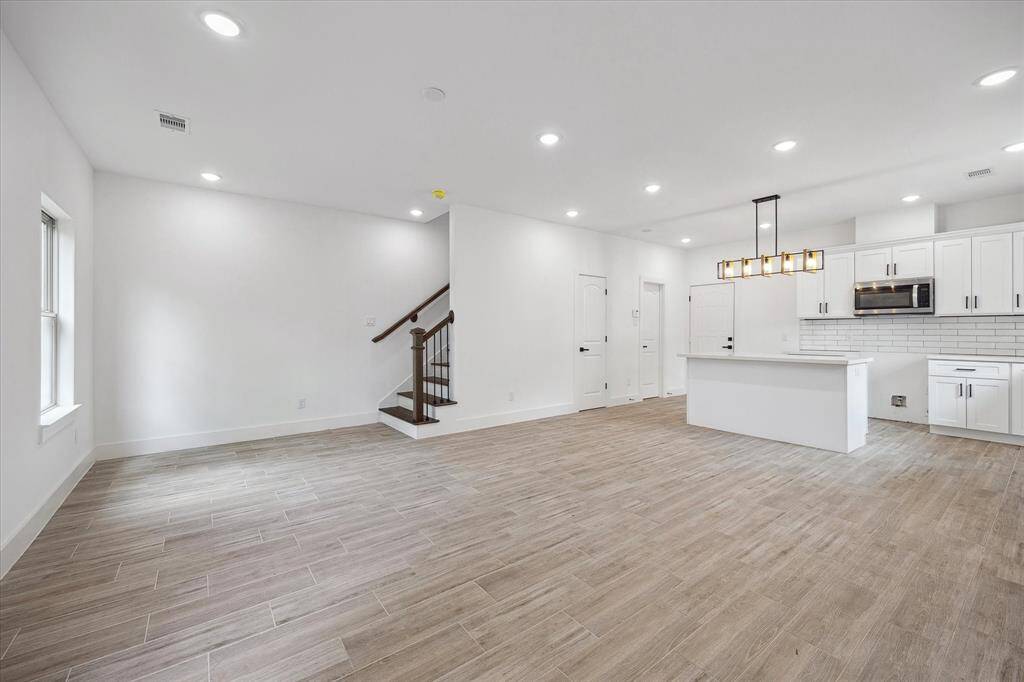 The spacious open living space has beautiful modern title, large, windows, and recessed lighting. The living room, dining area, and kitchen all flow seamlessly together.