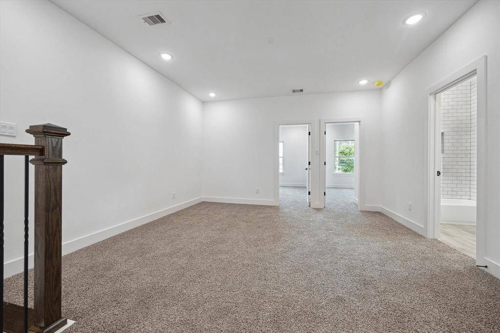 The upstairs living area features plush carpet, recessed lighting and access to the bedrooms.