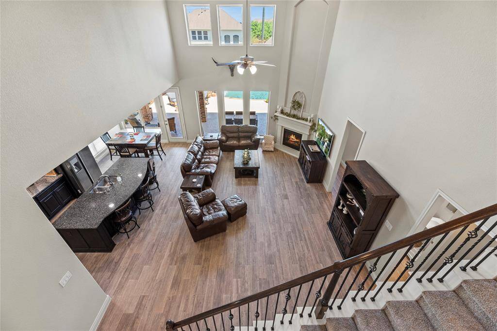 This spacious living area features high ceilings and large windows for abundant natural light. It includes a cozy fireplace, open floor plan, and a view of the outdoor Island inspired pool and spa.