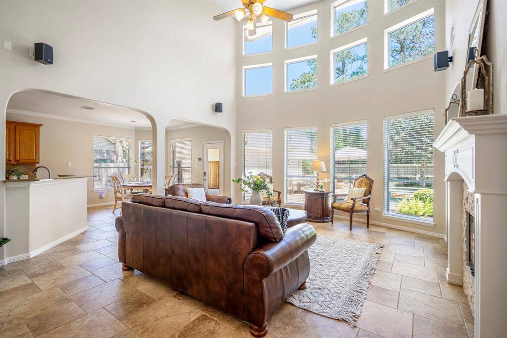 Moving closer to the fireplace, the beauty of the windows and the exquisite floors in the living room come into full view. To the left, arched openings lead seamlessly into the kitchen and breakfast areas, enhancing the home's open and inviting layout.