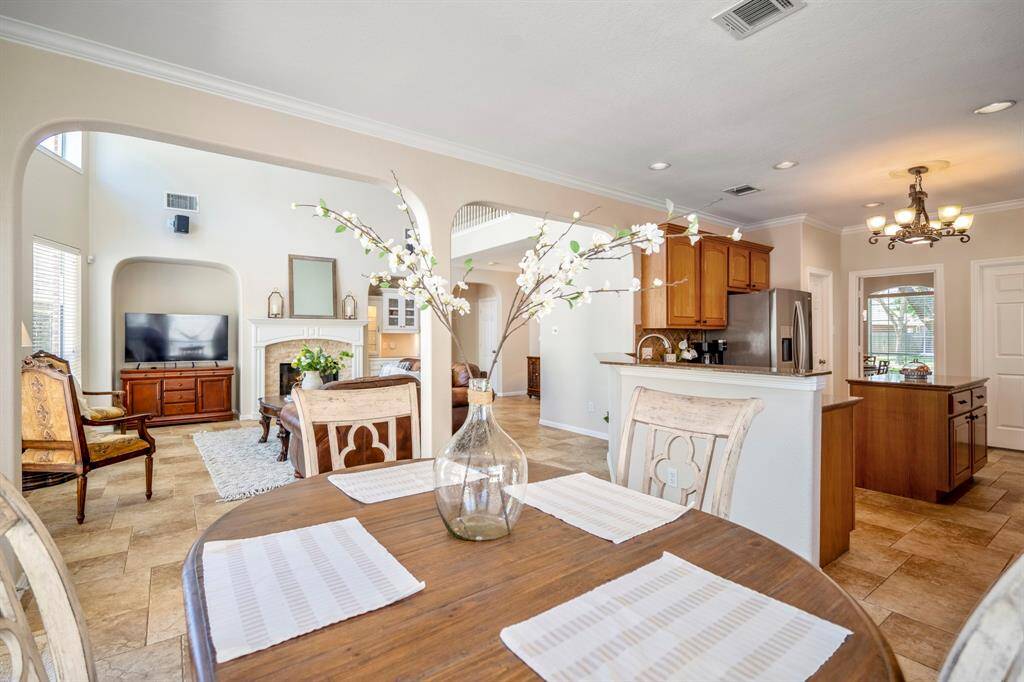 From the breakfast area, looking out, the space flows seamlessly into the kitchen on the right, while to the left, the living room is visible through the arched openings. Beyond the kitchen, the formal dining room can be seen through the doorway, creating an open, connected feel throughout the home.