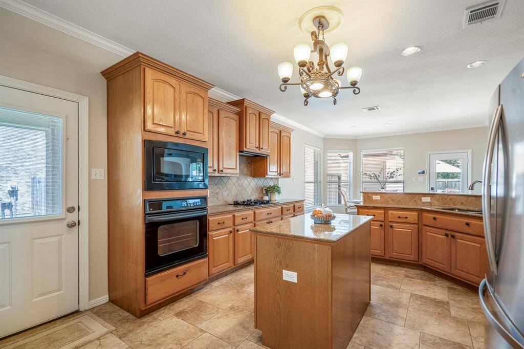 Standing near the pantry, this view offers a clearer look at the other side of the kitchen. To the left of the oven, there's a door leading to the driveway, while the laundry room is just out of sight behind us. The abundant cabinet space is highlighted, showcasing the kitchen's beautiful design and ample storage options.