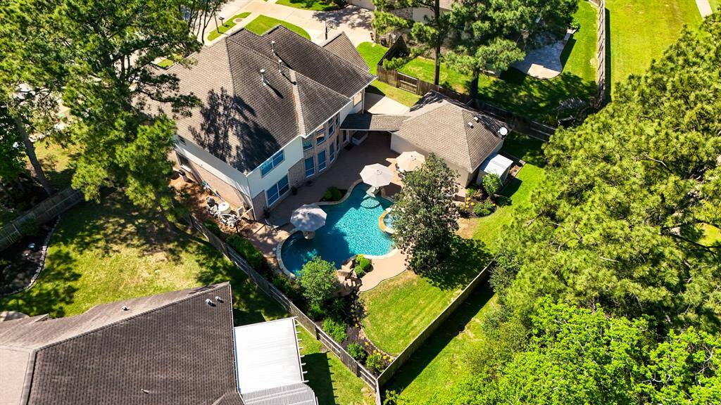 An aerial view showcasing the expansive lot and impressive layout of this home. The backyard features a resort-style pool, perfect for relaxation and entertaining, while the detached garage and storage shed offer additional space and convenience.