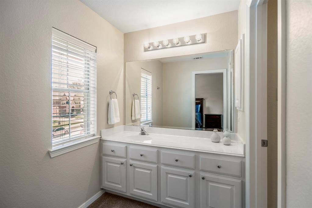 Stepping into the vanity area, you'll notice the large window that brings in natural light, along with plenty of counter space and a convenient medicine cabinet, offering both function and style..
