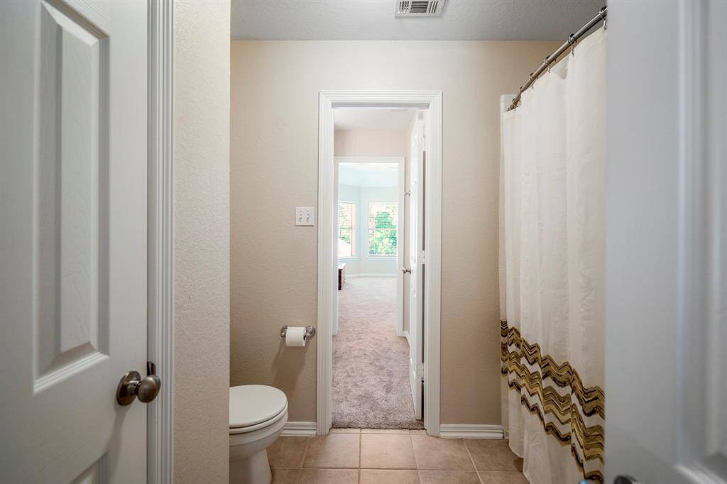 Moving into the bathroom, we can see through the open doorways into the vanity area and the bedroom beyond. To the left, a door leads to a spacious linen closet, adding extra storage convenience.