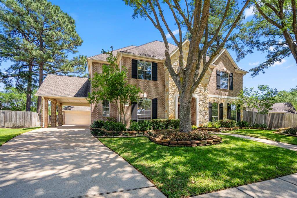 Another view of the front of the home, highlighting the extended driveway and stunning covered parking area to the left. The detached garage is tucked behind, offering both privacy and additional parking space.