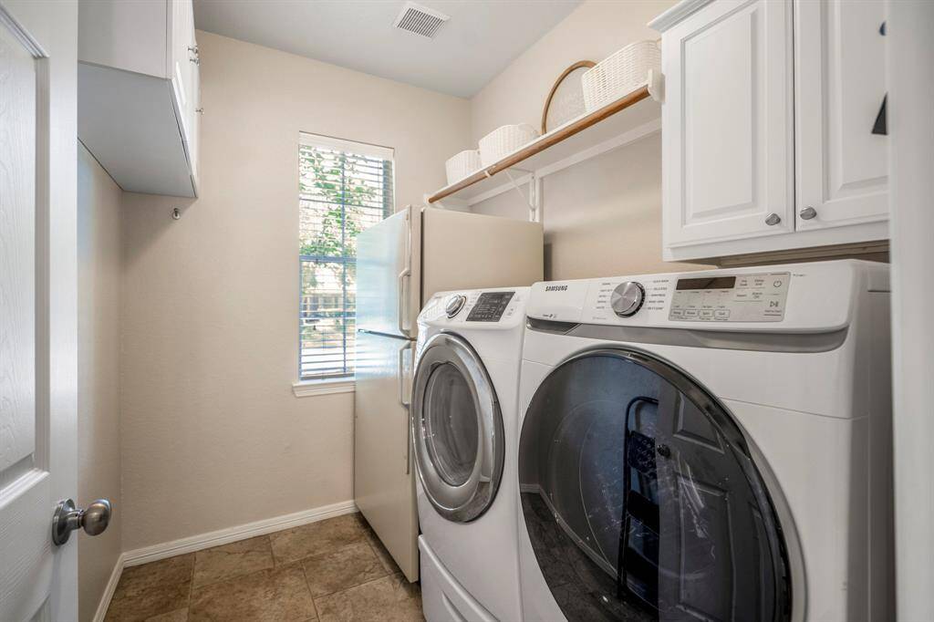 A peek inside the downstairs laundry room, conveniently located just off the kitchen. This functional space features built-ins, fridge space, and a window that overlooks the front yard, adding both utility and natural light.
