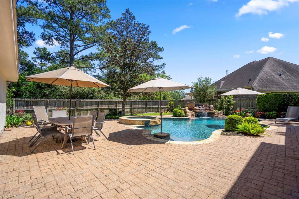 Stepping outside onto the paver patio, you'll be greeted by the exquisite pool with a cascading waterfall. The pool area features a hot tub, a beach entry with a table, and another seating area with an in-pool table, offering the perfect setting for relaxation and entertaining.