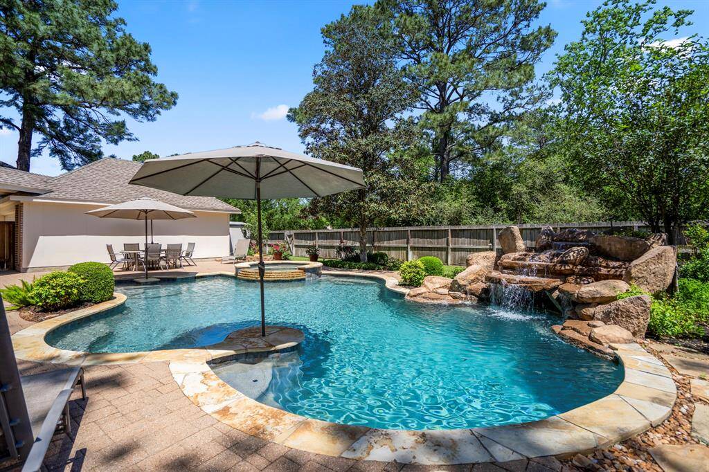 Another view of the stunning pool and waterfall, with the detached garage and storage shed visible off to the left. This spacious backyard offers not only a beautiful retreat but also convenient storage and extra space for your needs.