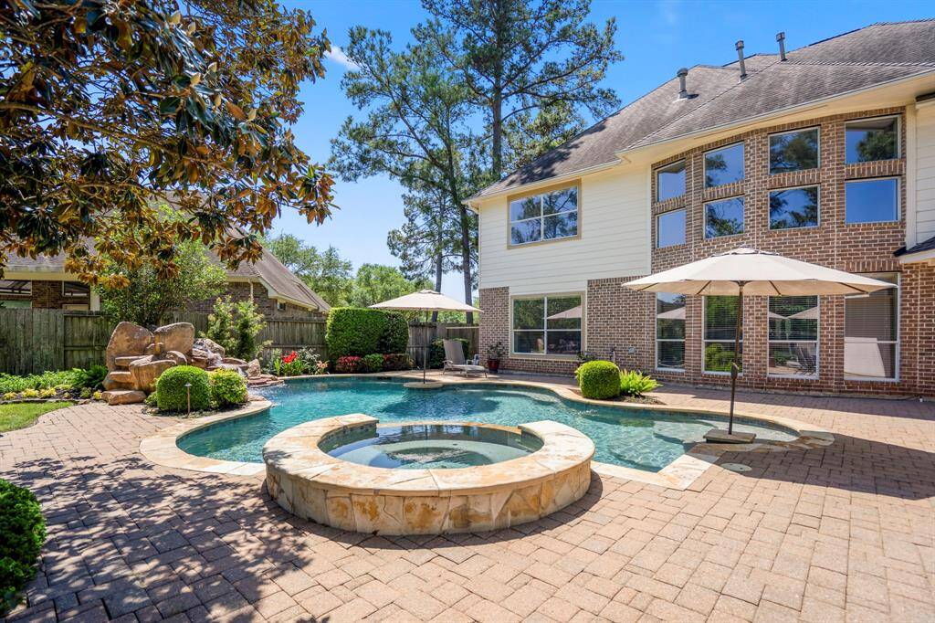From behind the hot tub, this view gives a glimpse of the back of the home, highlighting the paver patio that gracefully wraps around the pool. It’s the perfect setting for outdoor gatherings, offering easy access to both the pool and the home.