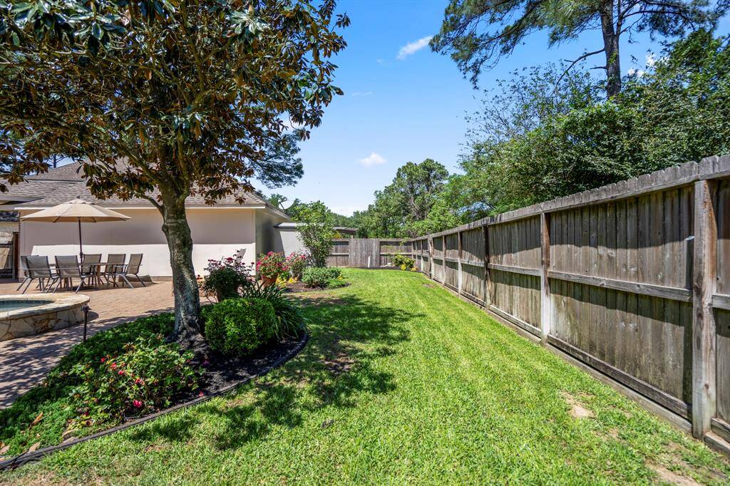 This view showcases the serene grassy space behind the pool, framed by a cedar privacy fence. The neatly tucked storage shed behind the garage is discreetly hidden, thanks to thoughtfully placed landscaping that adds to the beauty and privacy of the backyard.