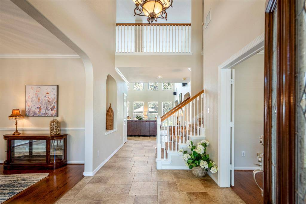 Step inside and be wowed! To the left, an elegant formal dining area is framed by an arched opening, while to the right, the home office is accessed through French doors. Straight ahead, the staircase leads to the second floor, and the living room boasts a stunning wall of windows that fill the space with natural light. The foyer features an art niche with a shelf, and overhead, a balcony provides a view of both the foyer and the living room, adding to the home's open and airy feel.