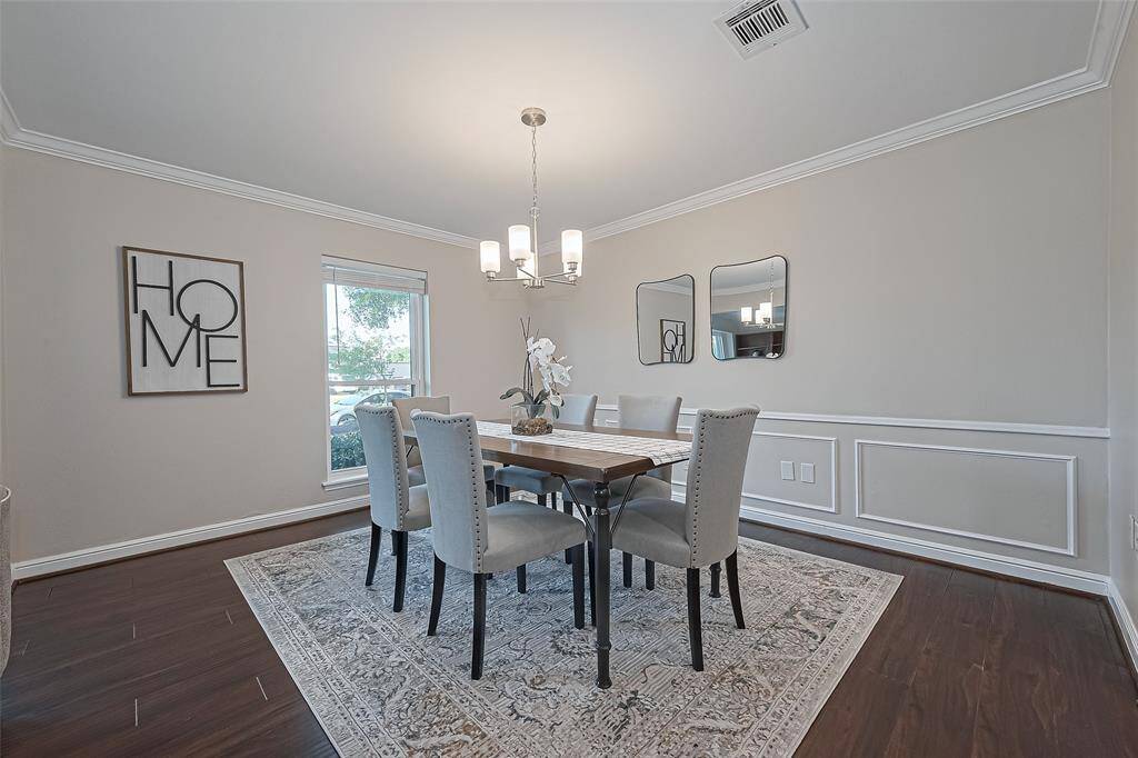 This spacious formal dining area is ideal for both everyday meals and special occasions, featuring rich wood floors and a beautiful light fixture that adds a touch of modern elegance.