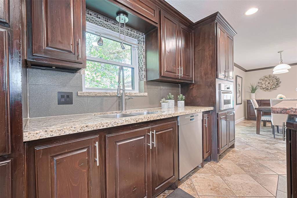 Framed by rich wood cabinetry that offers both elegance and generous storage, the kitchen sink is perfectly positioned beneath a wide window—inviting in natural light and garden views to brighten up daily routines.