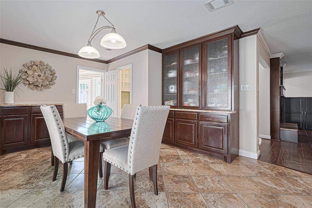 As we step into this charming breakfast area, you’ll immediately notice the custom built-in cabinetry with textured glass doors—perfect for displaying your favorite dishware or storing essentials out of sight.