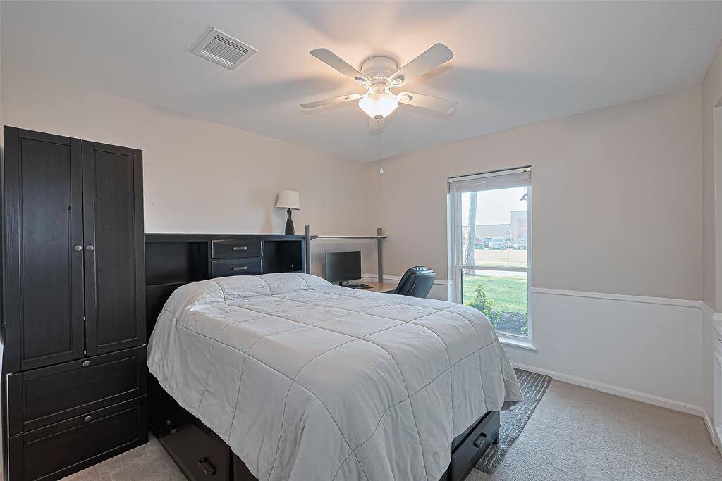 Located at the front of the home, this comfortable guest bedroom features a ceiling fan for added comfort and a large window that brings in soft, natural light throughout the day.
