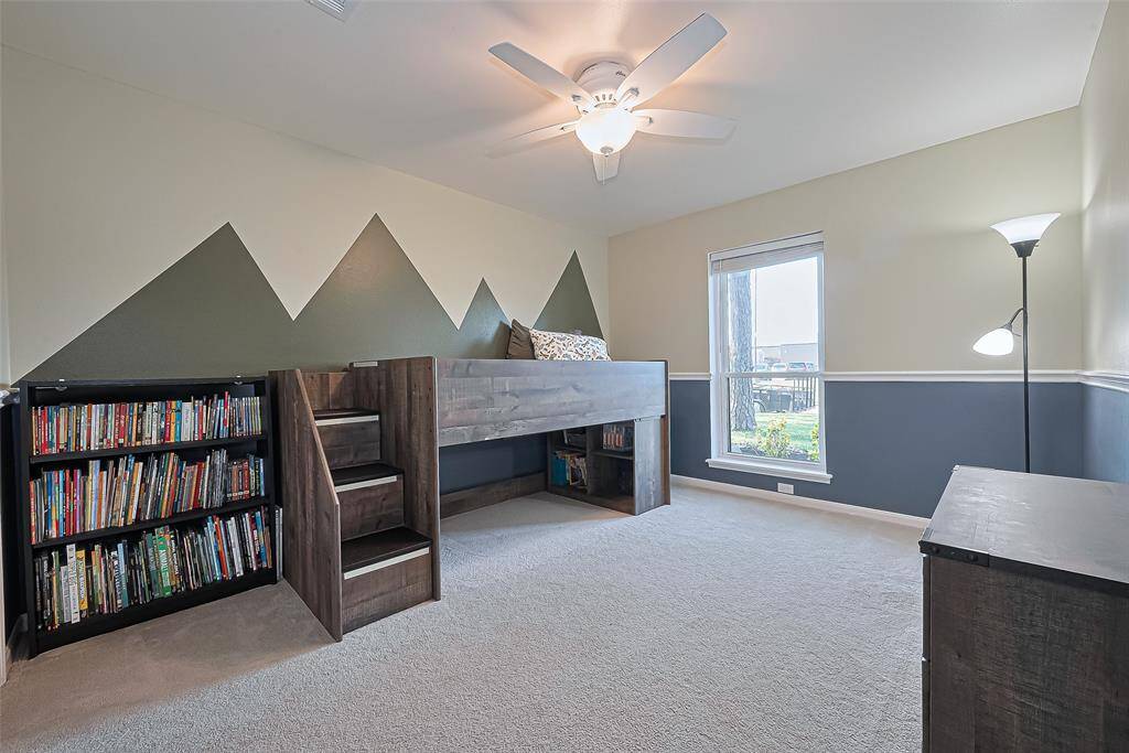 The second guest bedroom offers a cozy retreat with plush carpet underfoot, a tall window that welcomes natural light, and a ceiling fan to keep the space cool and comfortable.