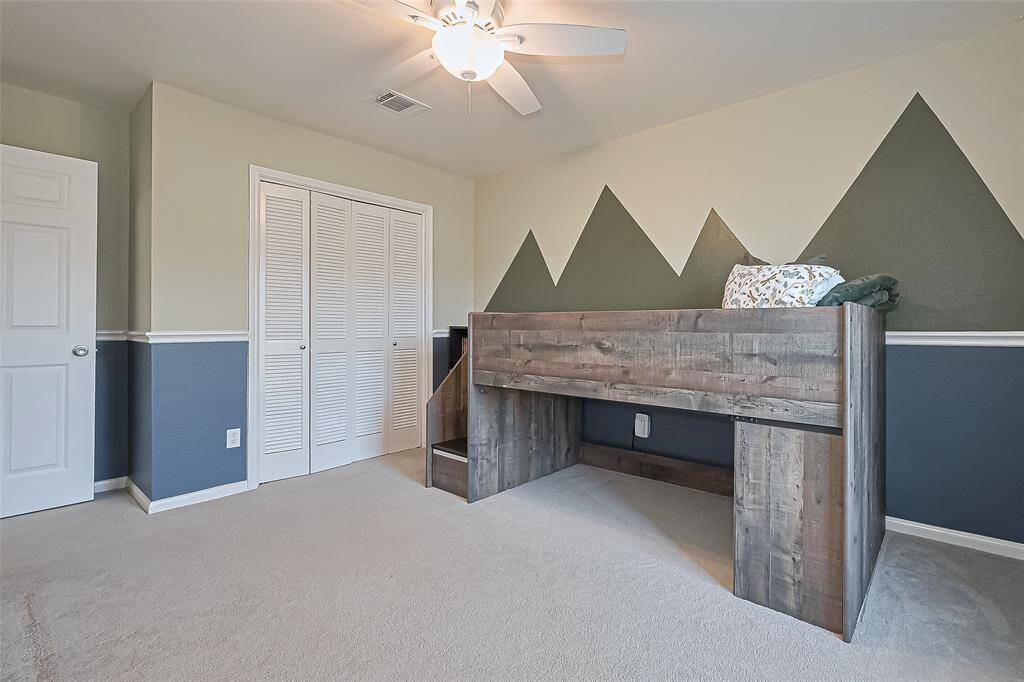 This room offers smart storage solutions with a spacious closet featuring double doors. The room is further accentuated by custom trim work.