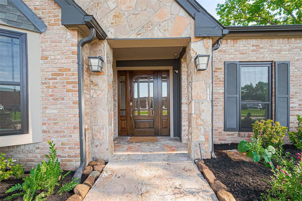Welcome guests in style with this charming stone-accented front entrance, featuring a beautiful wood door and a covered porch perfect for adding a warm, welcoming touch.