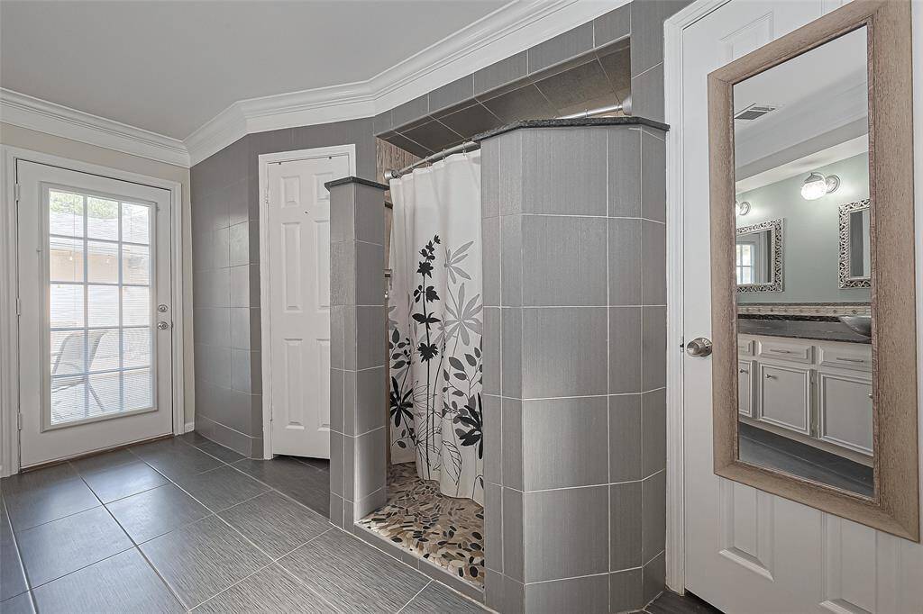 Just steps from the dual sinks, this stylish walk-in shower offers both privacy and elegance with its tile-wrapped entrance and natural stone flooring—plus, with direct access to the backyard patio, it’s perfect for a refreshing rinse after enjoying the outdoors!