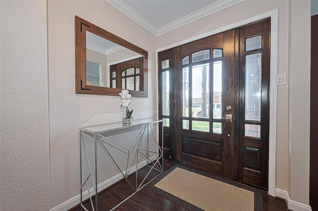 Step into a bright and inviting entryway where natural light pours through the stunning wood and glass front door, setting the tone for the warmth and charm found throughout the home.