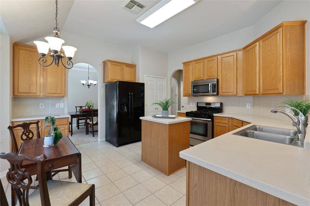 The kitchen boasts an island in the center, surrounded by cabinets and expansive counter space.