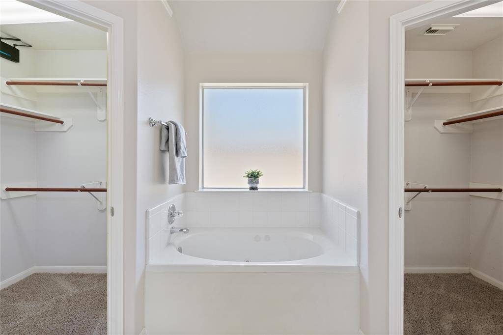 The garden bathtub is situated between the his and her walk-in closets. This provides ample space for storage and personal items.