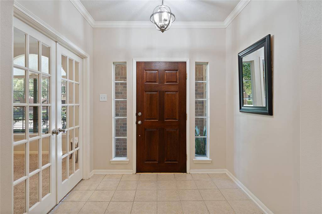 The front entrance features crown molding and elegant French doors that open into the private home office/study.