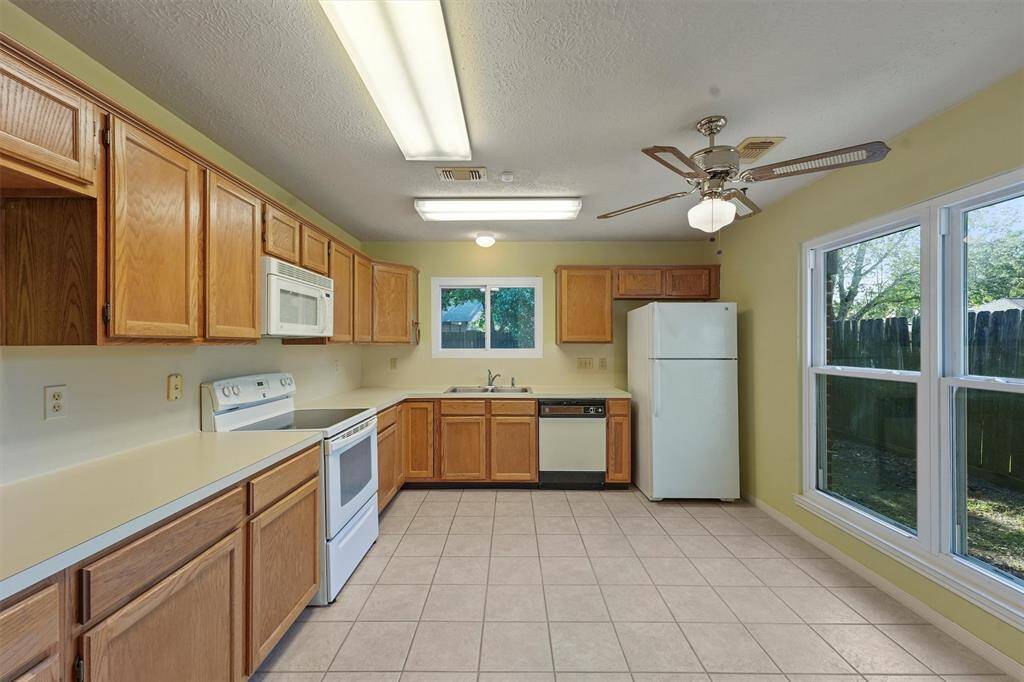 The kitchen features ample natural light. It has a spacious layout with tile flooring and a ceiling fan over the breakfast nook.