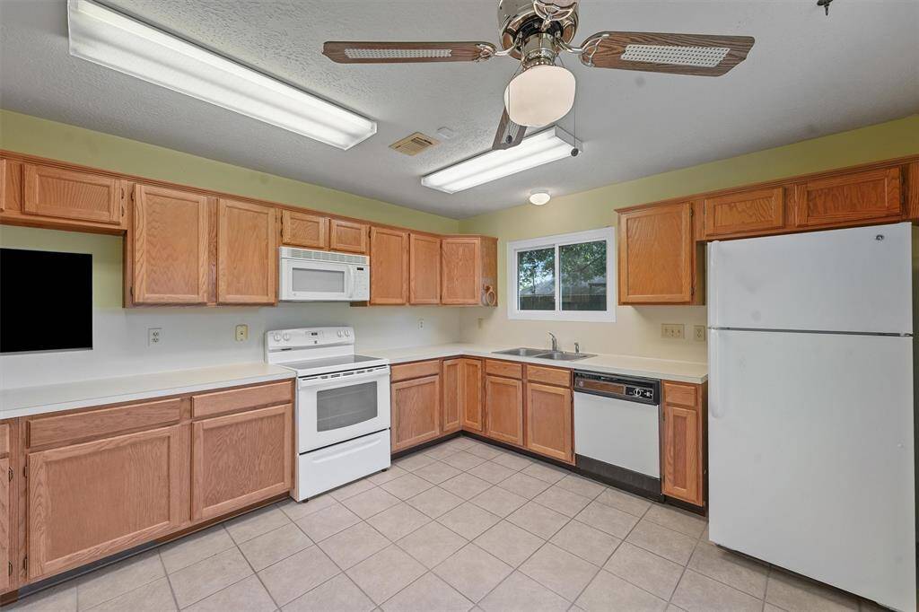 This kitchen features ample wooden cabinetry. A window above the sink provides natural light.