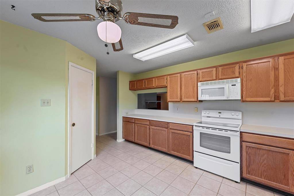 This kitchen includes a white electric stove and microwave, with a convenient pass-through window to the living room. Ample storage is provided by a spacious walk-in pantry.