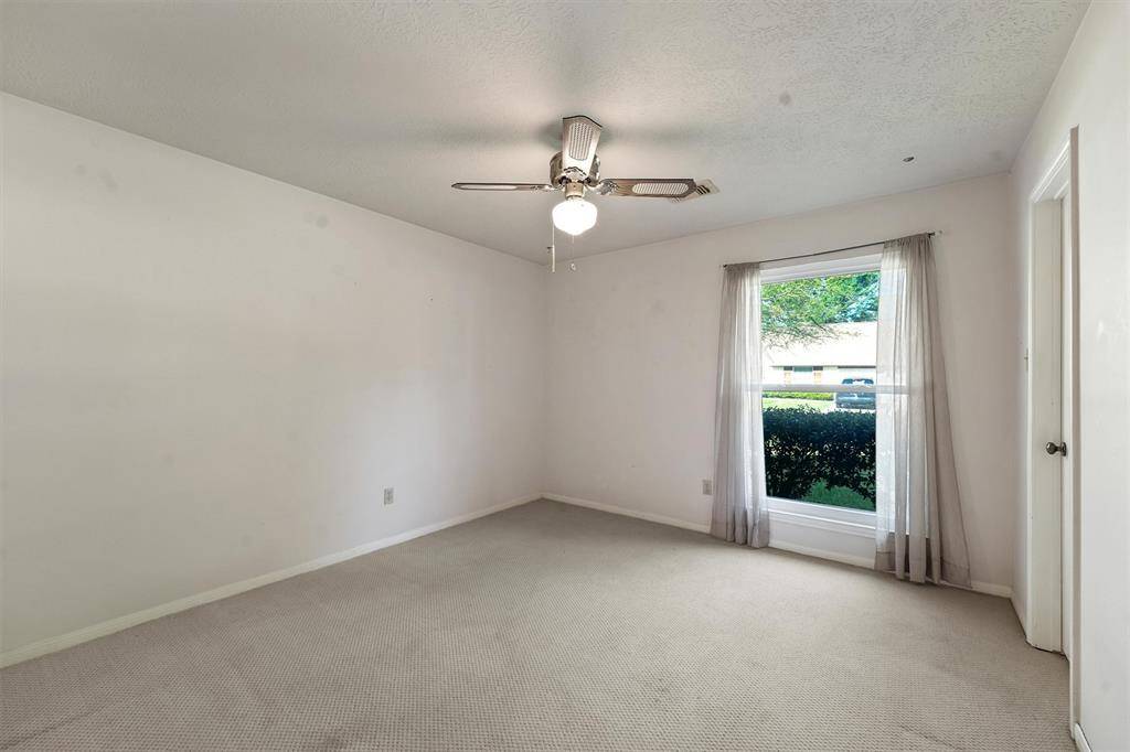Another large, bright bedroom with a large window providing natural light and a view of the front yard. It also has a large walk-in closet.