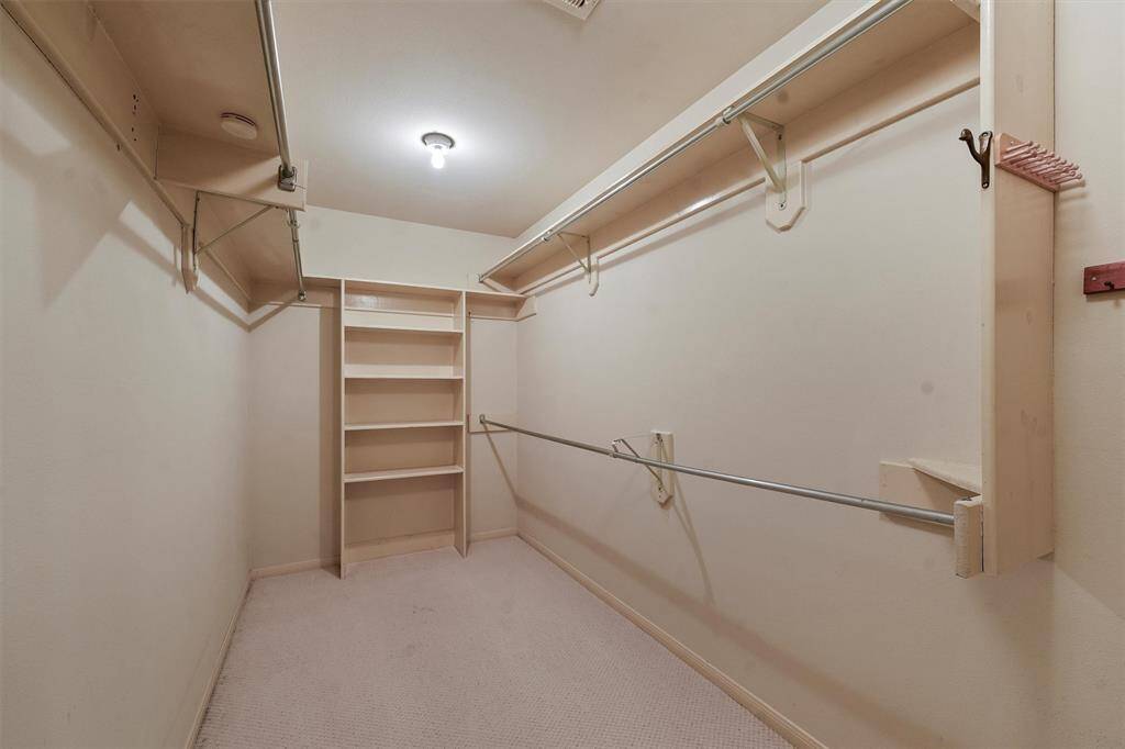 Spacious primary bedroom walk-in closet with ample shelving and hanging space, perfect for organizing clothing and accessories.